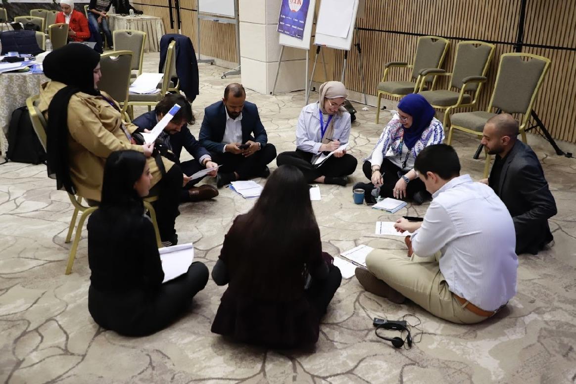 A group of youth gather in a circle on the floor at a Youth, Peace and Security workshop in Amman, Jordan