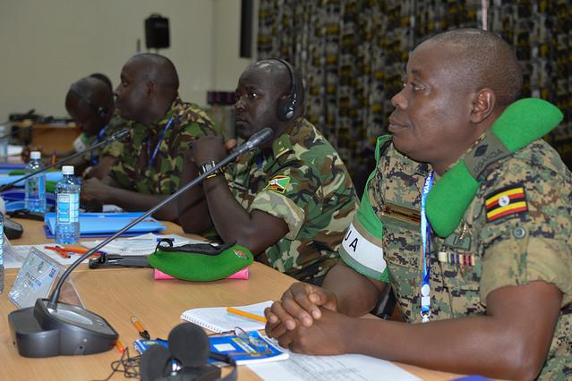 Men in uniform sit at a table in front of microphones